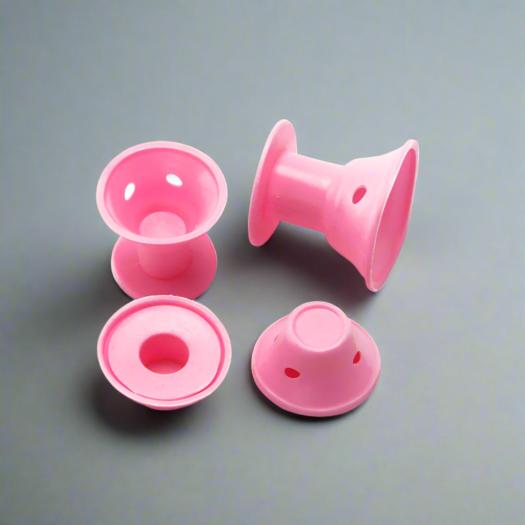 Gros plan sur bigoudis en silicone rose sur fond gris luxe.