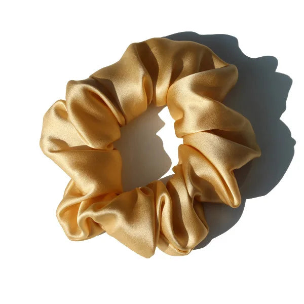 Chouchou en soie jaune, élégant et doux au toucher, avec finition satinée, idéal pour préserver les cheveux tout en ajoutant une touche chic et raffinée à votre coiffure