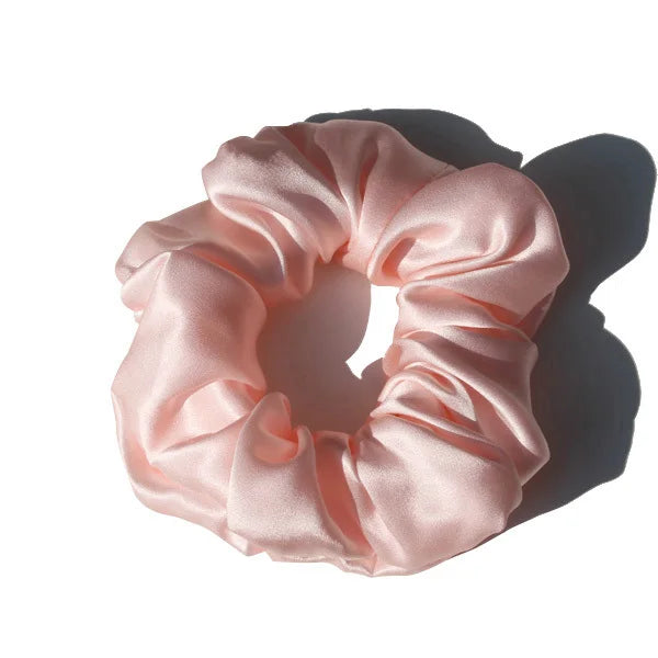 Chouchou en soie rose, élégant et doux au toucher, avec finition satinée, idéal pour préserver les cheveux tout en ajoutant une touche chic et raffinée à votre coiffure