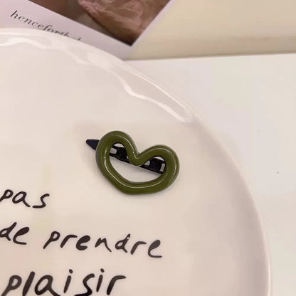 Barrette verte en forme de cœur, élégante et mignonne, idéale comme accessoire pour les cheveux avec une touche de douceur. 