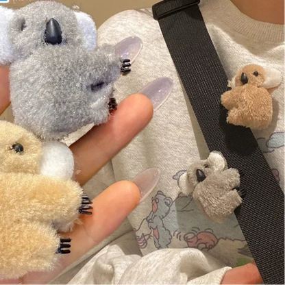 Pinces à cheveux peluche Koala  grise ou beige présentés sur un sac et des doigts manucurés - l'accessoire mignon et pratique - Parfaite pour les petites filles comme pour les adultes, cette pince originale et kawaii permet de maintenir vos cheveux tout en apportant une note ludique et mignonne. 