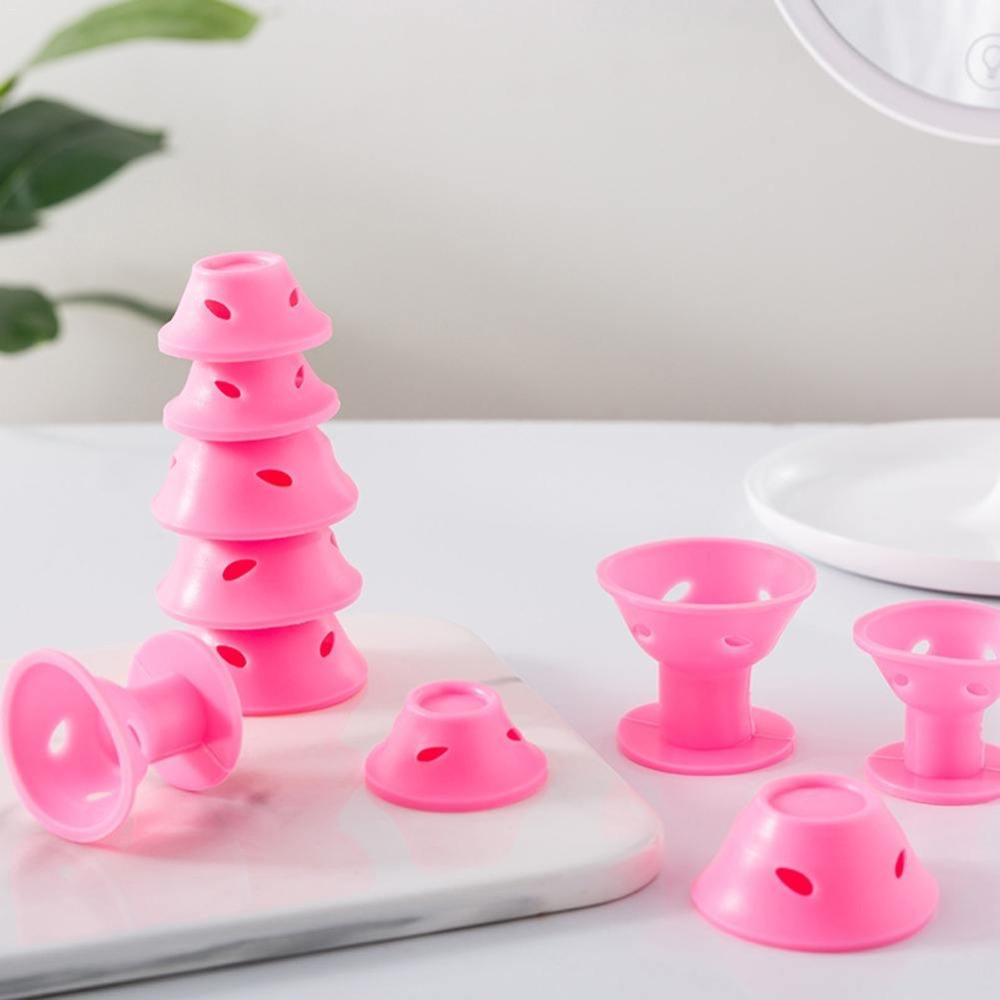 Gros plan sur bigoudis en silicone rose posés sur un plan de travail avec miroir.