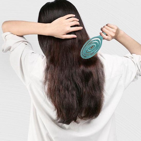 Femme de dos avec Brosse à cheveux pour boucles, antistatique et démêlante, idéale pour cheveux bouclés ou frisés, avec picots souples pour un coiffage sans frisottis.