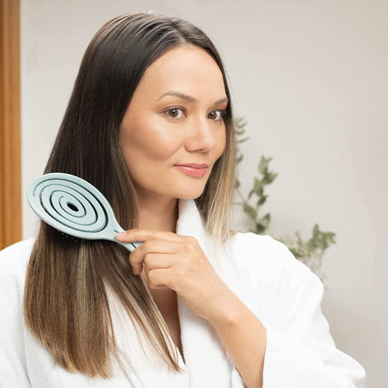 Femme qui se brosse avec Brosse à cheveux pour boucles, antistatique et démêlante, idéale pour cheveux bouclés ou frisés, avec picots souples pour un coiffage sans frisottis.