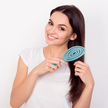 Belle femme souriante avec Brosse à cheveux pour boucles, antistatique et démêlante, idéale pour cheveux bouclés ou frisés, avec picots souples pour un coiffage sans frisottis.