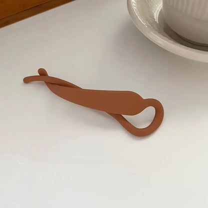 Pince à cheveux en plastique rouge, de taille moyenne, conçue pour maintenir les cheveux en place de manière pratique et sécurisée, avec un design simple et fonctionnel.