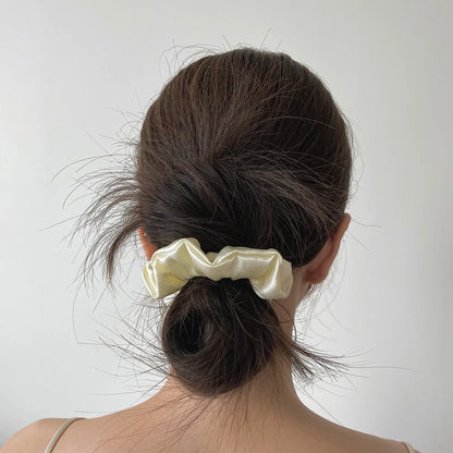Chouchou en soie blanche, élégant et doux au toucher, avec finition satinée, parfait pour protéger les cheveux tout en apportant une touche sophistiquée à vos coiffures