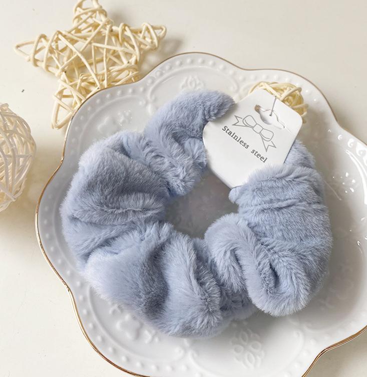 Chouchou en fausse fourrure bleu clair posé sur une assiette blanche décorative, présentation élégante du produit.