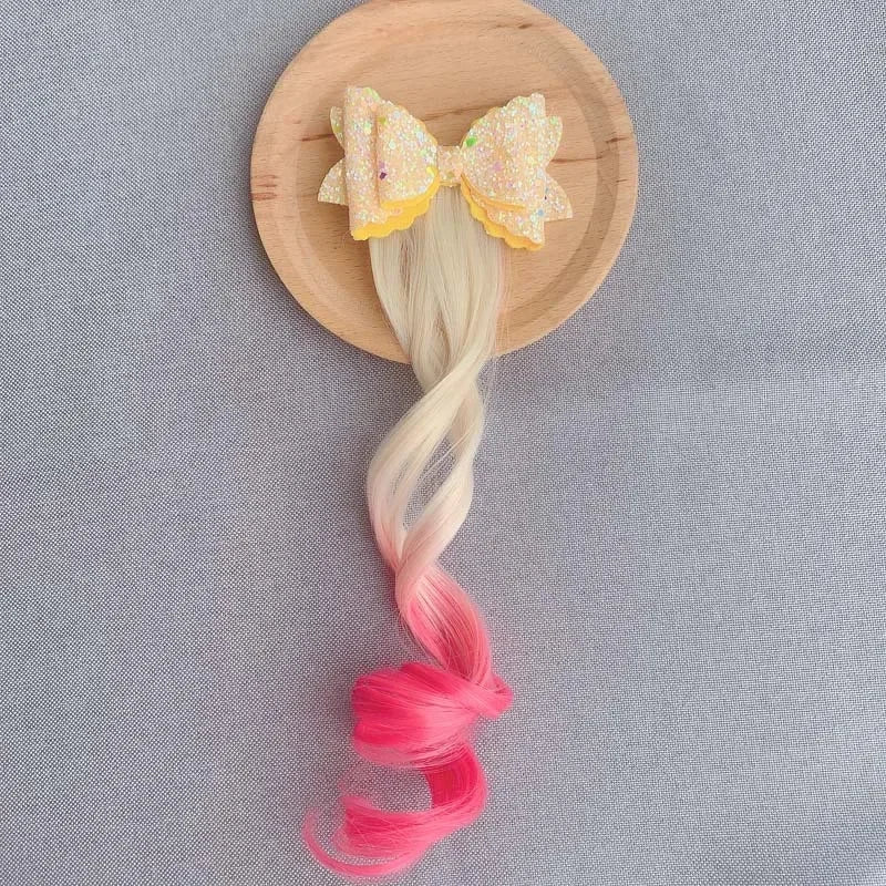 Extension de cheveux avec barrette en forme de nœud jaune et rose, ajoutant une touche douce et féminine à la coiffure
