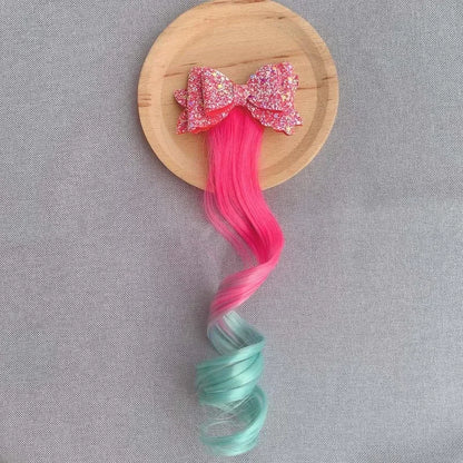 Extension de cheveux avec barrette en forme de nœud rose et vert, ajoutant une touche douce et féminine à la coiffure