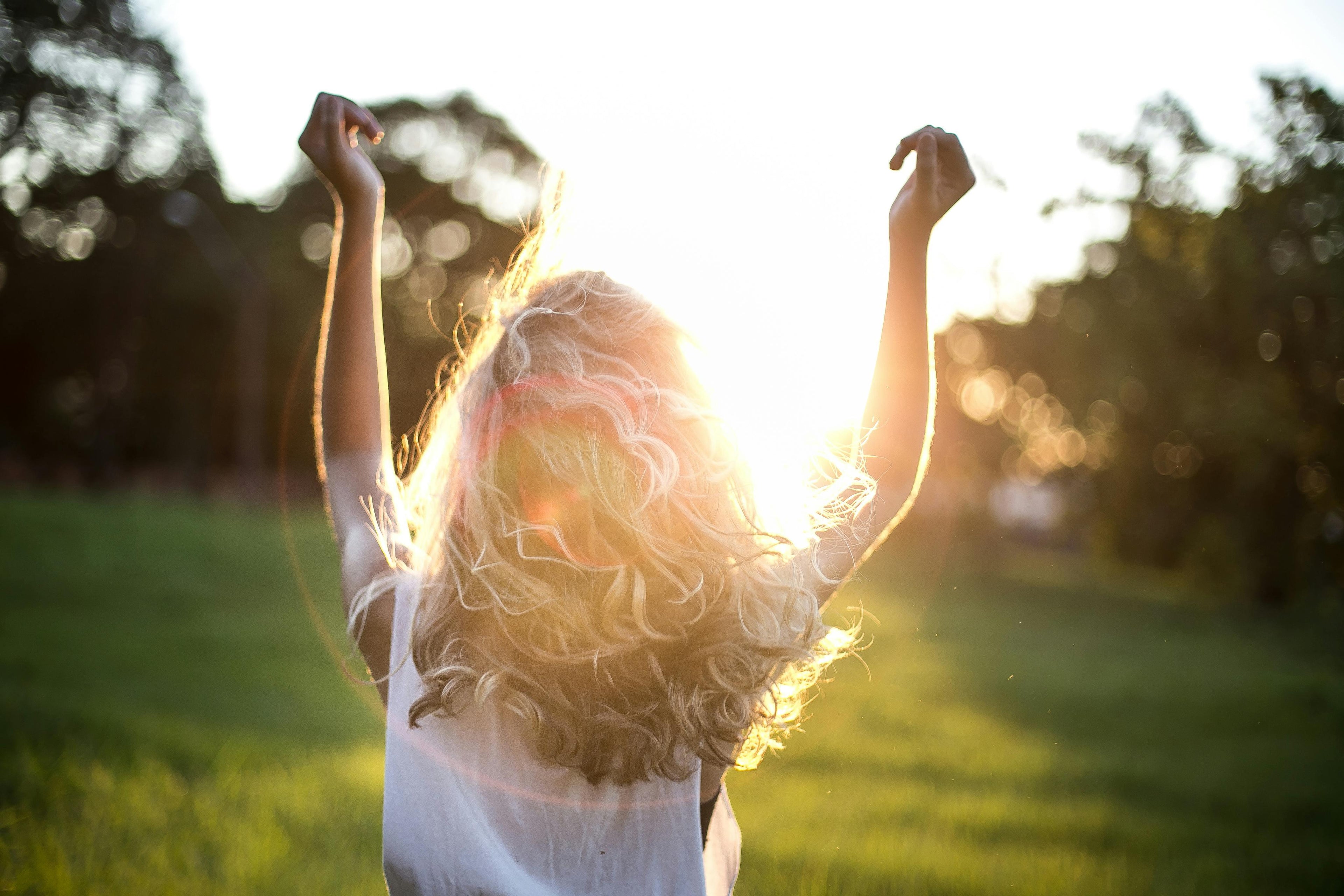 Femme aux cheveux blonds illuminés par le soleil — soins capillaires naturels Cheveux Soyeux