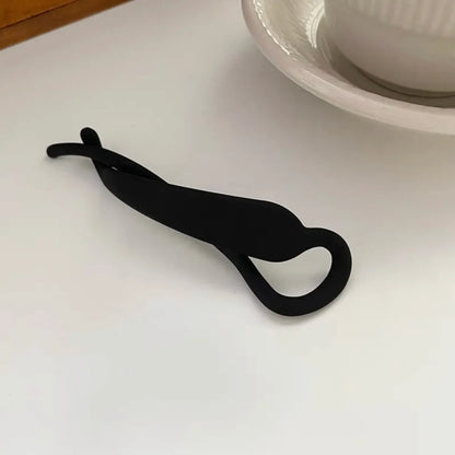 Pince à cheveux en plastique noir, de taille moyenne, conçue pour maintenir les cheveux en place de manière pratique et sécurisée, avec un design simple et fonctionnel