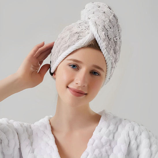 Fille en train de porter une serviette de bain blanche pour cheveux, conçue pour protéger et sécher les cheveux après le lavage.